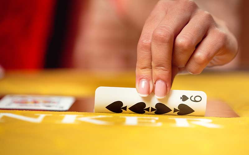 Live Online Baccarat dealer holding cards